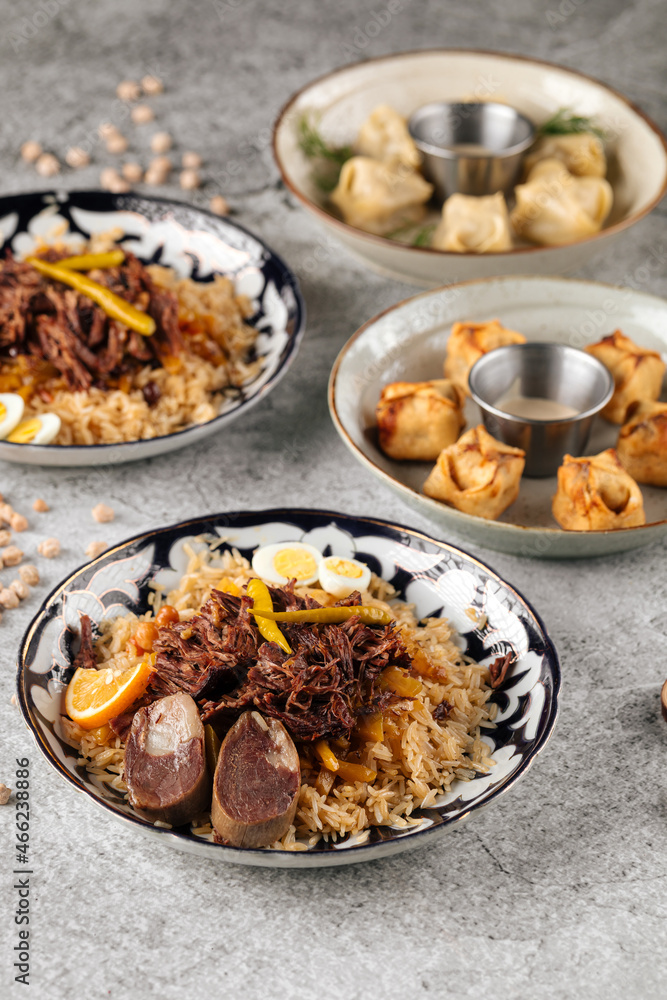 Fototapeta premium Various oriental dishes pilaf and manti on the gray background