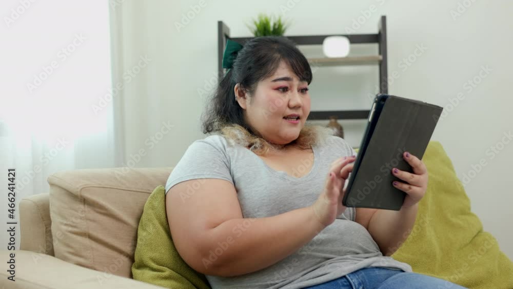 Body positive plus size female holding tablet taking selfie photo using smartphone camera. Happy woman plus size video call in living room. Body positive plus size female holding tablet taking selfie photo using smartphone camera. Happy woman plus size video call in living room.