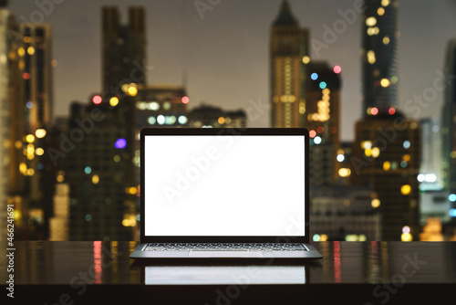 laptop computer on workspace white blank screen display city on