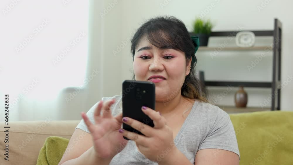 Body positive plus size female holding mobile phone taking selfie photo using smartphone camera. Happy woman plus size video call in living room. Body positive plus size female holding mobile phone taking selfie photo using smartphone camera. Happy woman plus size video call in living room.