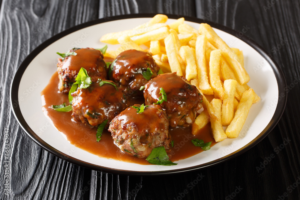 Belgian Boulets sauce lapin meatballs in apple gravy and French fries closeup in the plate on the table. Horizontal Belgian Boulets sauce lapin meatballs in apple gravy and French fries closeup in the plate on the table. Horizontal