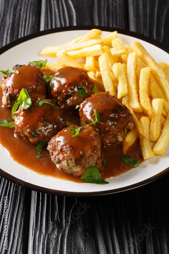 Boulet a la liegeoise or boulet sauce lapin is a Belgian dish of meatballs in apple sauce and French fries closeup in the plate on the table. Vertical photo