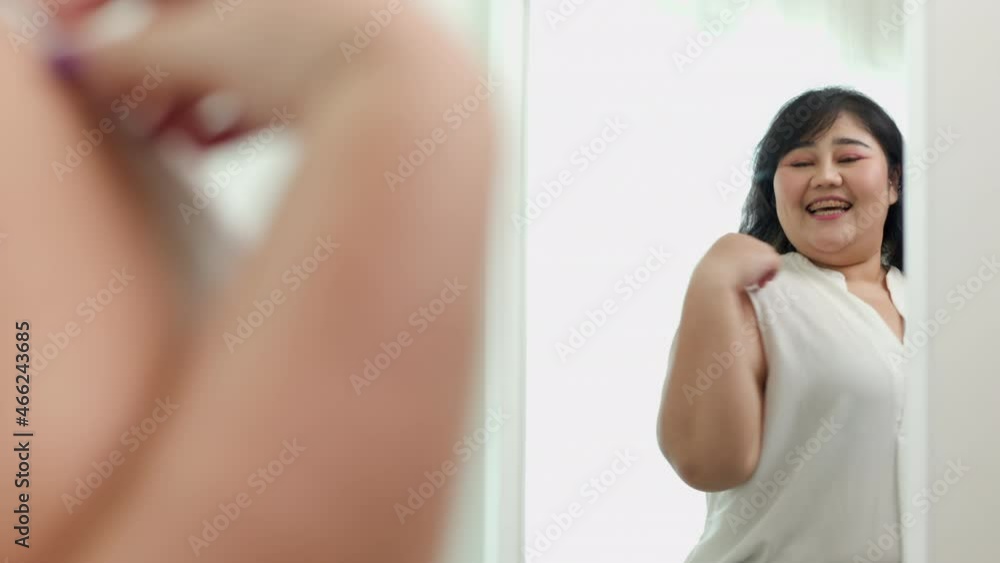 Body positive plus size female clothing. Body positive plus size woman happily and is proud of herself looking at mirror at home Body positive plus size female clothing. Body positive plus size woman happily and is proud of herself looking at mirror at home