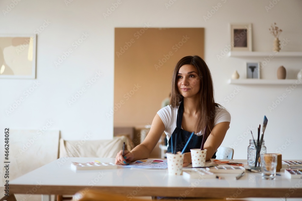 Beautiful Female Artist In Her Studio. Female drawing in album with watercolor paints and paintbrush Beautiful Female Artist In Her Studio. Female drawing in album with watercolor paints and paintbrush