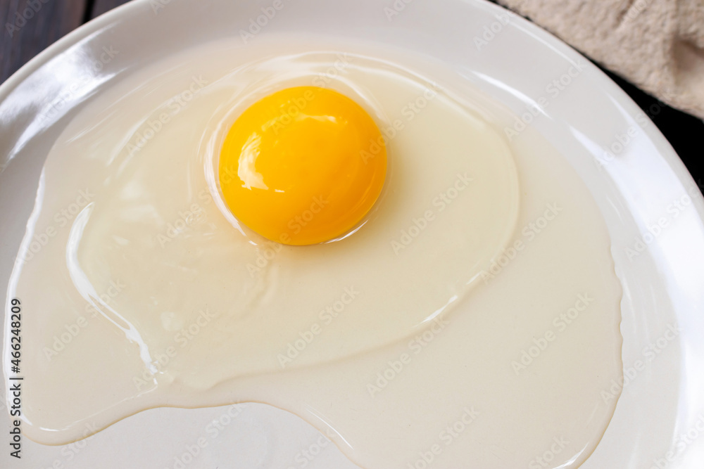 Organic free range egg and egg yolk on white dish; top view on wooden table background. Organic free range egg and egg yolk on white dish; top view on wooden table background.