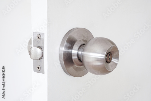 Stainless door knob with key hole on white wooden door 