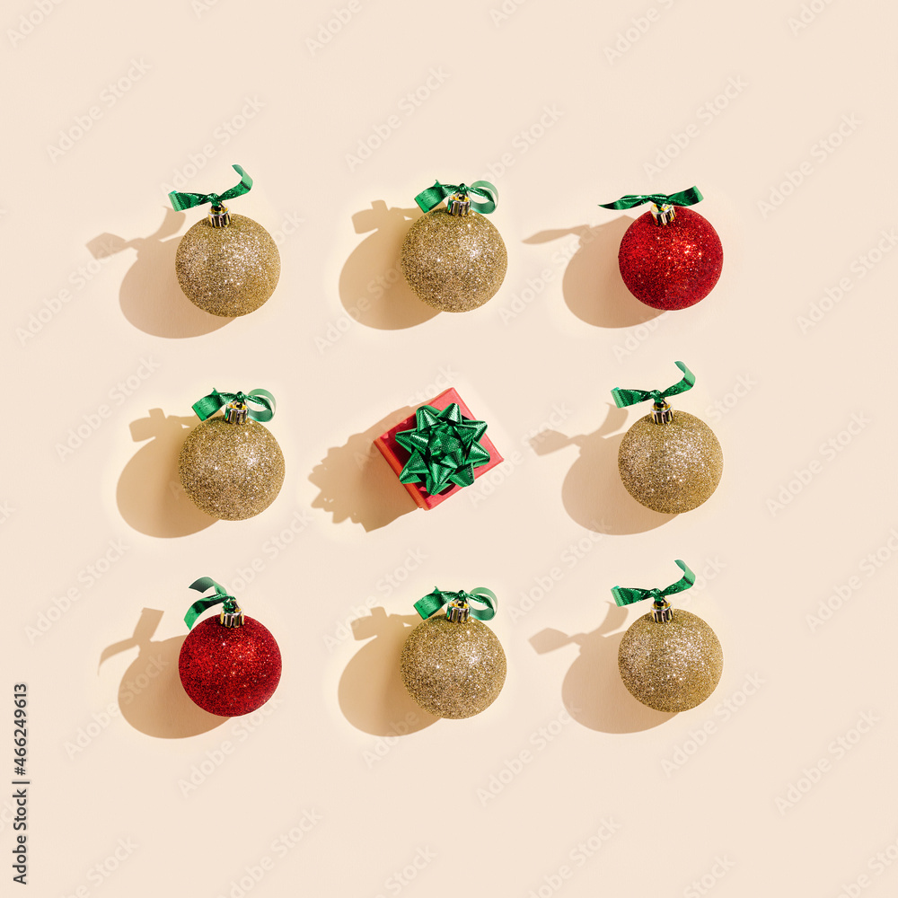 New Year holiday square composition, golden and red christmas balls and small gift box on pale pink