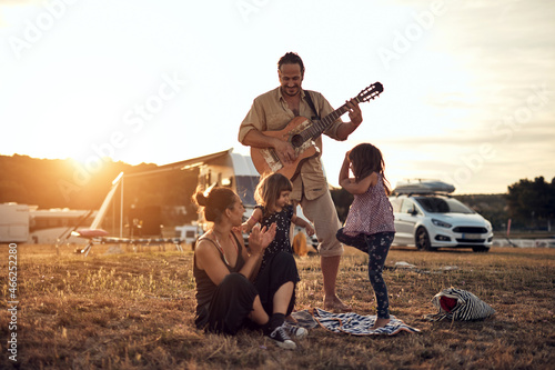 Family on a vacation, singing, playing music on a guitar and enjoying summertime vibes.