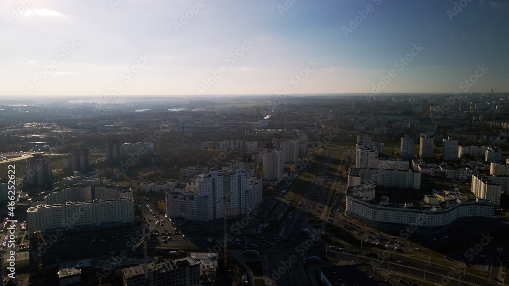 Flight over city blocks. Multi-storey buildings and construction site. Flying in the backlight of the setting sun. Aerial photography.