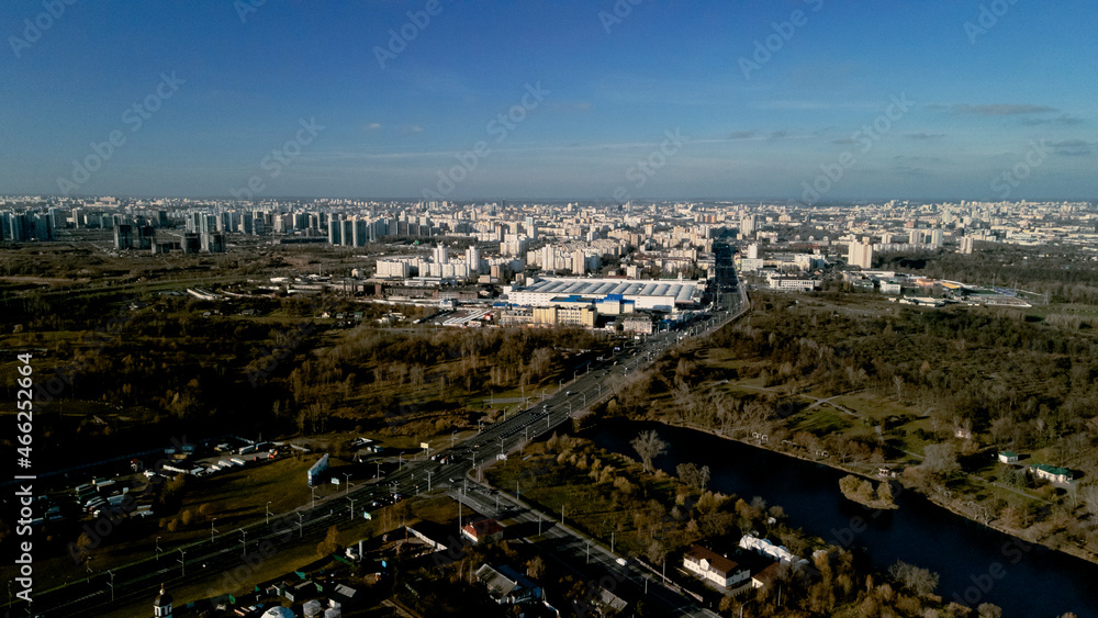 City autumn park with a river. Flying in the suburbs. On the horizon are high-rise buildings. Aerial photography.