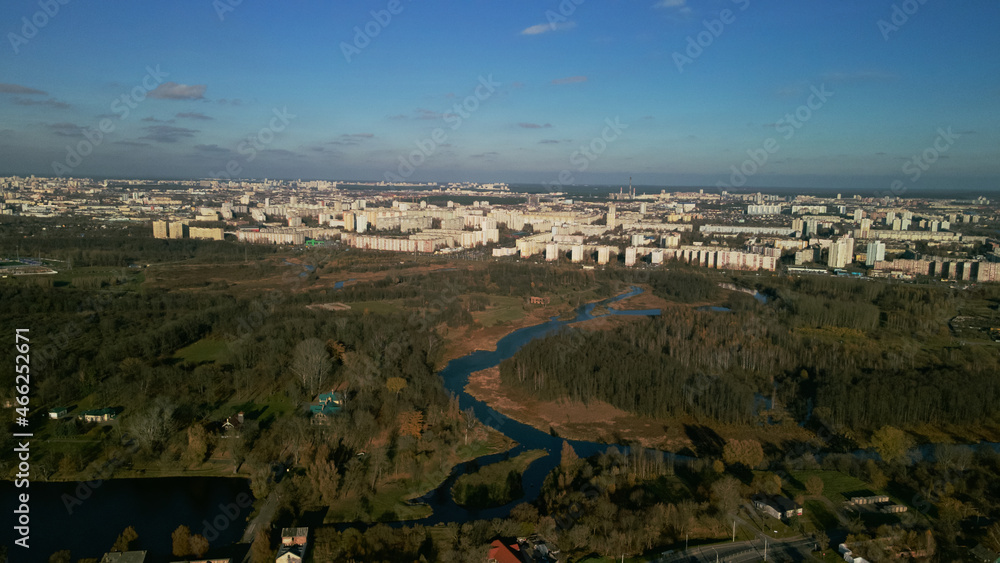 City autumn park with a river. Flying in the suburbs. On the horizon are high-rise buildings. Aerial photography.
