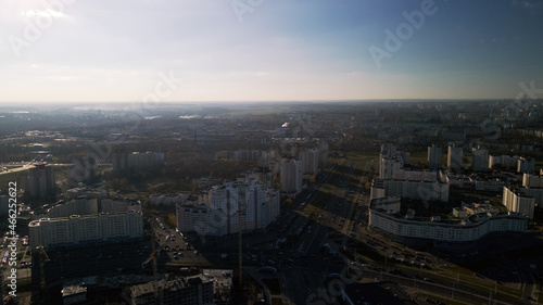 Flight over city blocks. Multi-storey buildings and construction site. Flying in the backlight of the setting sun. Aerial photography.