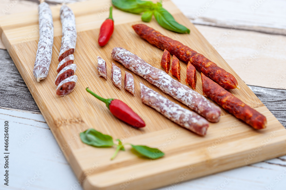 assorted mini salami with vegetables on wooden board