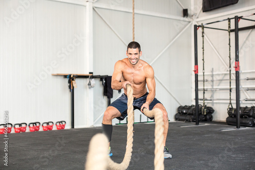 Men with battle ropes exercise in the fitness gym