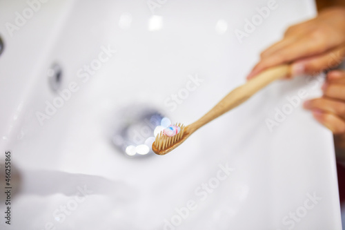 Ecologe wooden Toothbrush with toothpaste under water jet at home, healthy hygiene concept