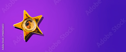 Gold star on a purple background. Hard shadow. Copy space. Place for your text.Flat lay. New Year s banner.