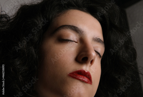 Close-up photo of woman with closed eyes and make-up. Nude eyes, red lips. 