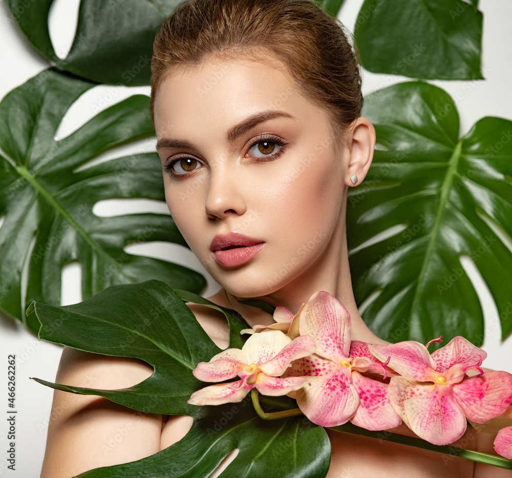 Beautiful woman with green leave near face and body. Closeup girl's face with green leave. Pretty girl in Skin care beauty treatments concept. Model with pink tropical orchid near face. Brown makeup. Beautiful woman with green leave near face and body. Closeup girl's face with green leave. Pretty girl in Skin care beauty treatments concept. Model with pink tropical orchid near face. Brown makeup.