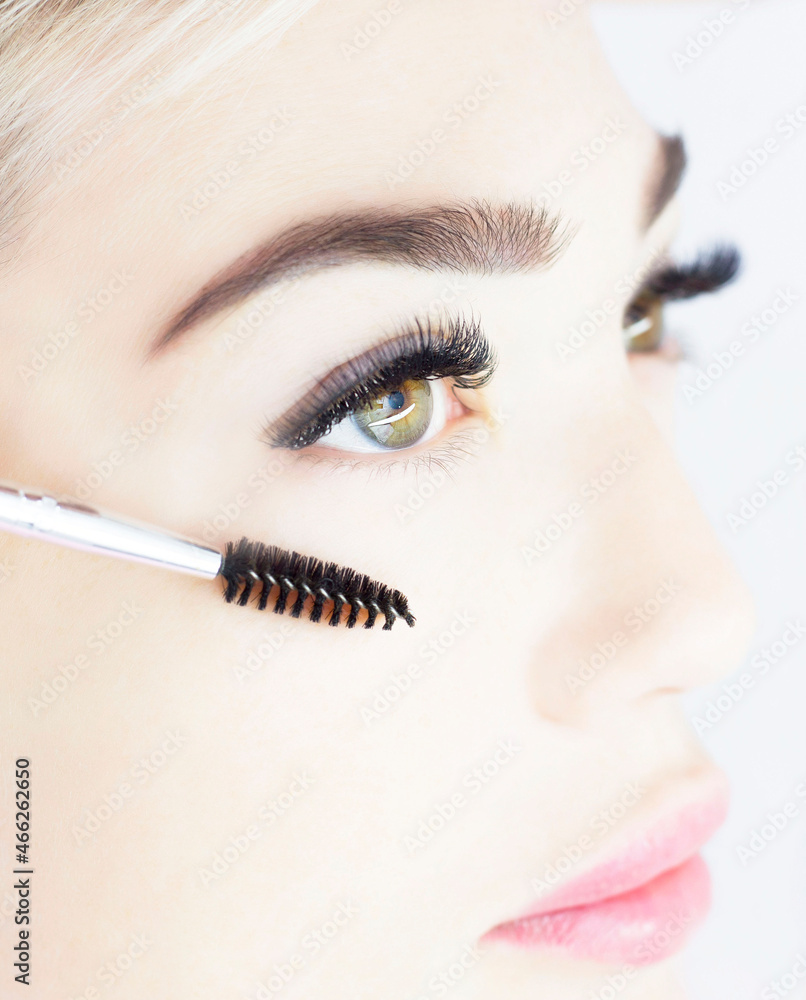 The girl is undergoing an eyelash extension procedure. Beautiful close-up of the eyes, thick black eyelashes. The concept of artificial eyelashes, a trend.