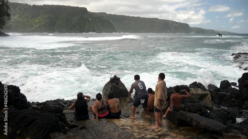 Hawaiian kids are trying to stop huge waves. Black lava rocks and crashing waves on beautiful Keanae Peninsula on the Road to Hana. photo