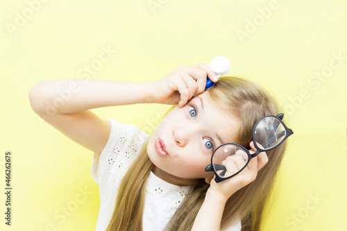 Obraz na plátně A beautiful baby with long hair holds a container with lenses and glasses in her hands