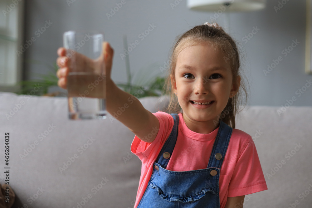 Happy little girl offer crystal still mineral water from glass, small child recommend daily dose of clean aqua. Happy little girl offer crystal still mineral water from glass, small child recommend daily dose of clean aqua.