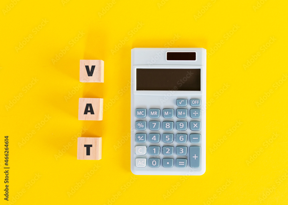 Mini calculator and wooden cubes with text VAT on yellow background. Value Added Tax. Finance and money. Flat lay, top view. Mini calculator and wooden cubes with text VAT on yellow background. Value Added Tax. Finance and money. Flat lay, top view.