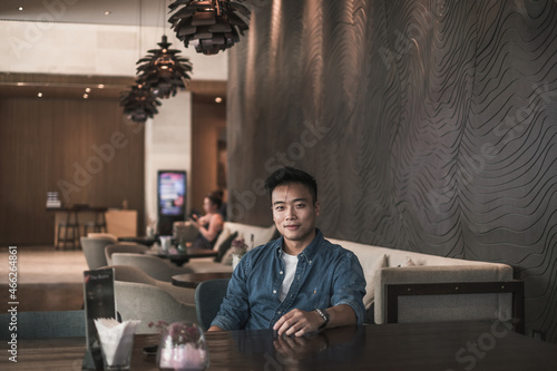Asian young handsome man sitting in coffee shop and smiling. Chinese guy, millennials life, lifestyle in the big city, Modern Asia, coffee break