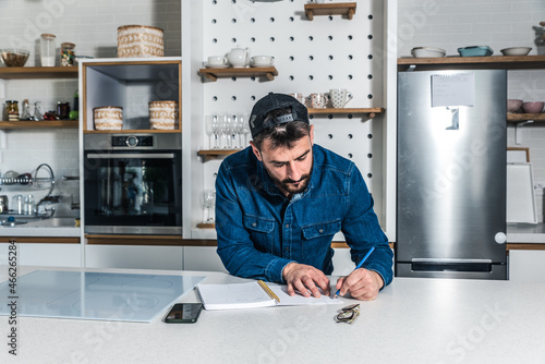 Young freelancer businessman planning and organizing business from his home. Creative man standing in the kitchen getting ideas and solutions for new project.