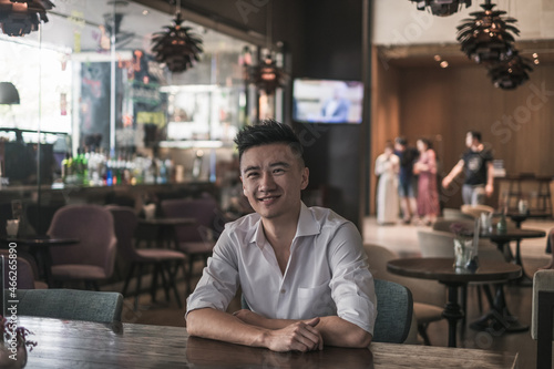 Asian young handsome man sitting in coffee shop and smiling. Chinese guy, millennials life, lifestyle in the big city, Modern Asia, coffee break