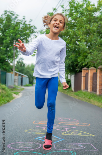 Child jumping classics on the street. Selective focus.