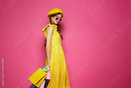 cheerful woman with multicolored bags posing pink background