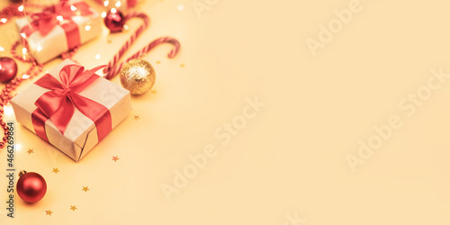 Christmas and New Year blurred backdrop with copy space. Festively decorated  Gift boxes,  cane lollypops, christmas balls on golden background.