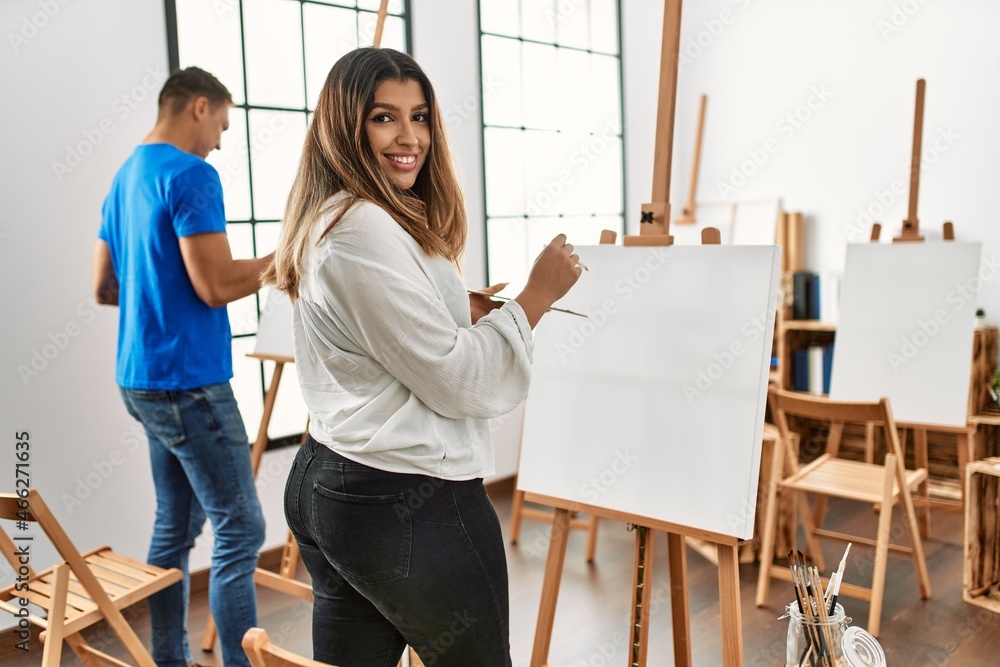 Two students smiling happy painting at art school. Two students smiling happy painting at art school.
