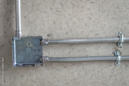 Electrical conduit for cable routing between electrical distribution panel with Galvanized electrical junction box and Pipe of electricity line installed in buildings. Selective focus.