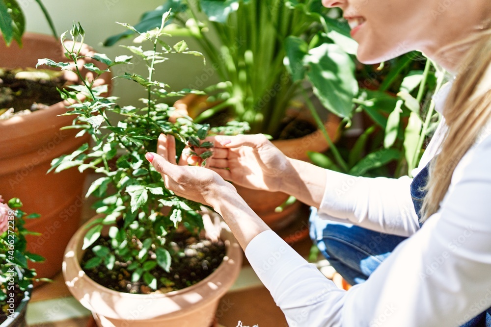 Obraz premium Young blonde woman smiling happy working at home terrace garden.