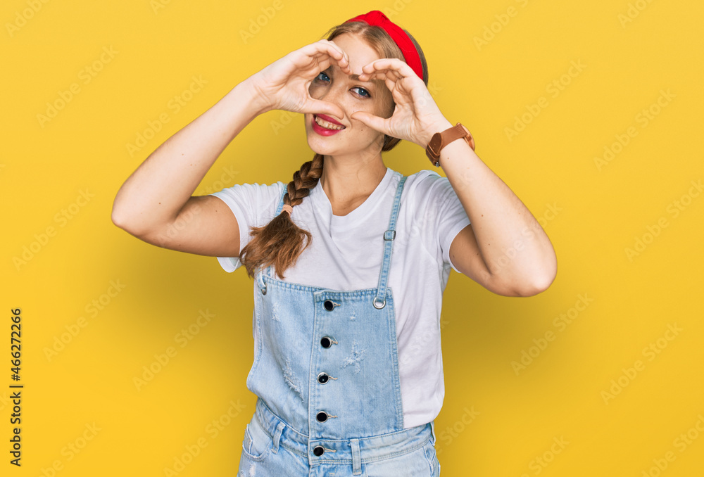 Young caucasian girl wearing casual clothes doing heart shape with hand and fingers smiling looking through sign Young caucasian girl wearing casual clothes doing heart shape with hand and fingers smiling looking through sign