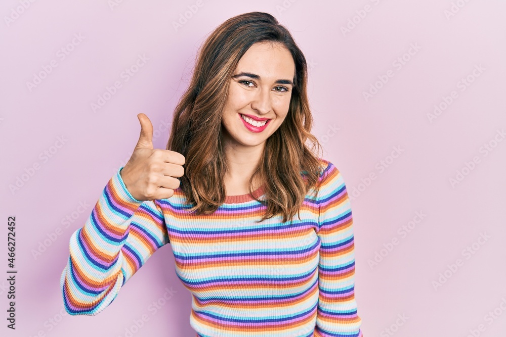 Young hispanic girl wearing casual clothes doing happy thumbs up gesture with hand. approving expression looking at the camera showing success.