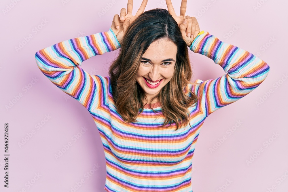 Fototapeta premium Young hispanic girl wearing casual clothes posing funny and crazy with fingers on head as bunny ears, smiling cheerful