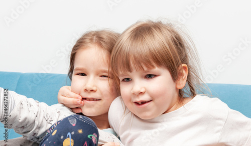 Two young elementary school age children, sisters, siblings, kids fooling around together at home smiling, funny quirky portrait, face closeup. Humor, having fun, family togetherness bonding concept