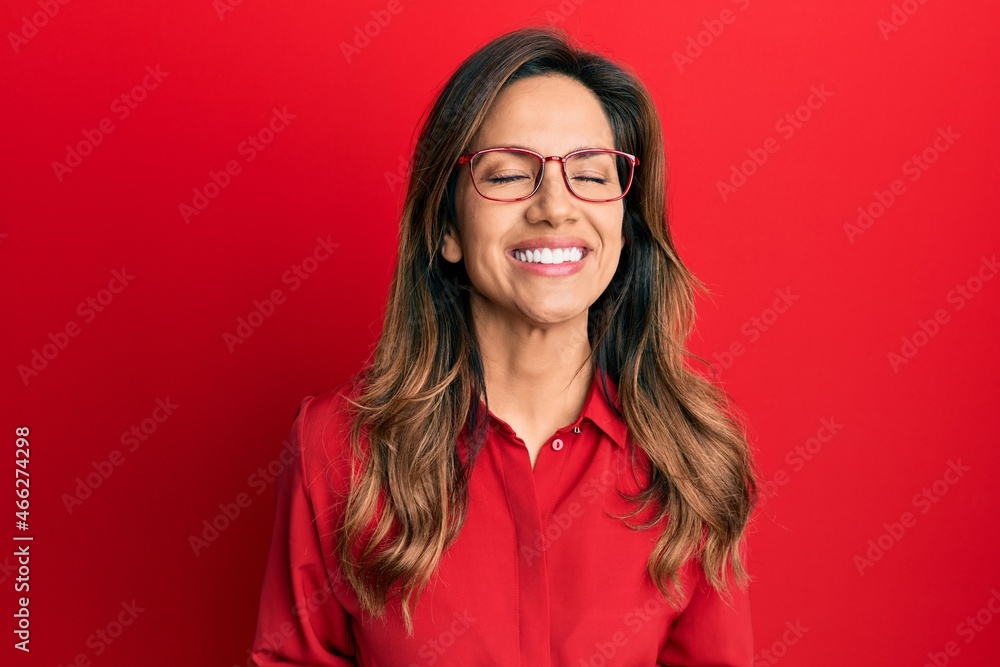Young latin woman wearing casual clothes and glasses very happy and excited doing winner gesture with arms raised, smiling and screaming for success. celebration concept. Young latin woman wearing casual clothes and glasses very happy and excited doing winner gesture with arms raised, smiling and screaming for success. celebration concept.