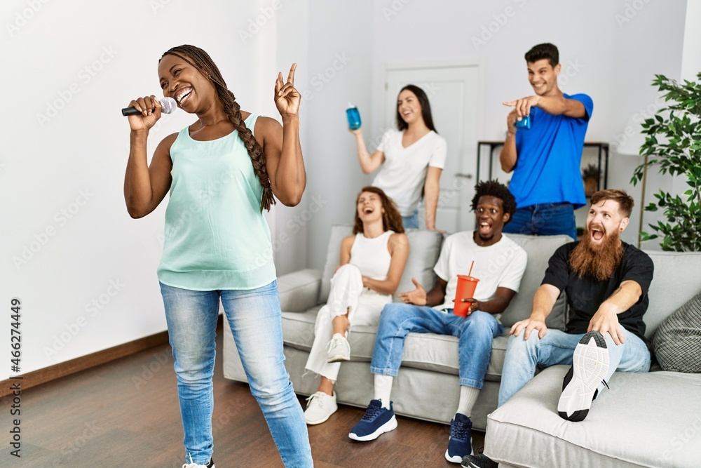 Group of young friends having party singing song using microphone at home. Group of young friends having party singing song using microphone at home.