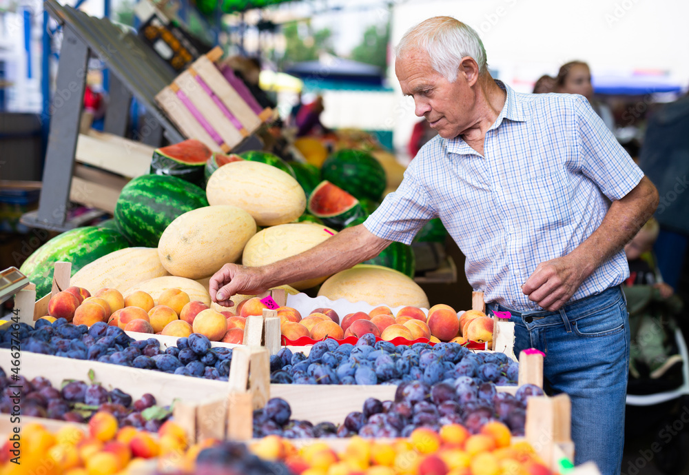 retired european man buying plums peaches nectarine in market