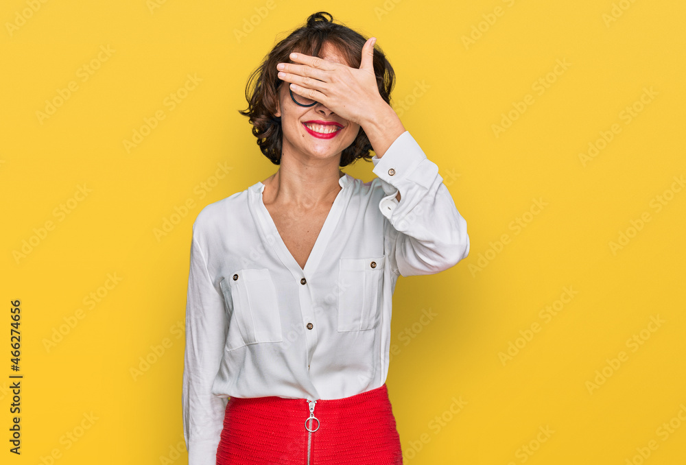 Young hispanic woman wearing business style and glasses smiling and laughing with hand on face covering eyes for surprise. blind concept.