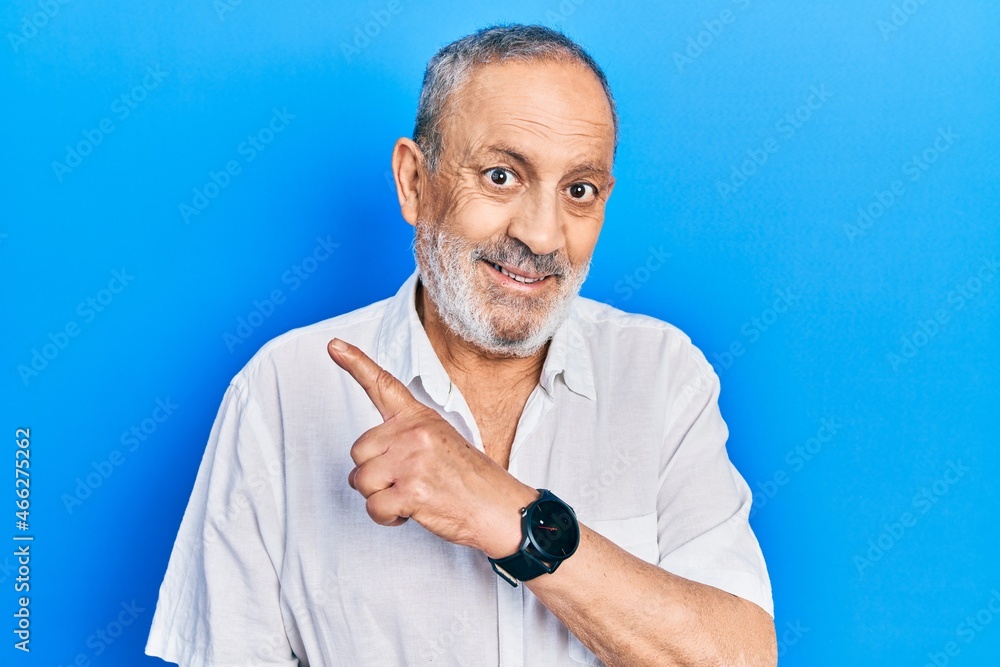 Handsome senior man with beard wearing casual white shirt cheerful with a smile of face pointing with hand and finger up to the side with happy and natural expression on face Handsome senior man with beard wearing casual white shirt cheerful with a smile of face pointing with hand and finger up to the side with happy and natural expression on face