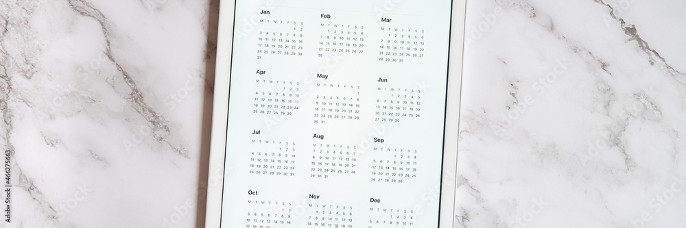 tablet computer with an open app of calendar for unspecified date year without date on a gray marble background. concept business or to do list goals with technology using. top view, flat lay. banner tablet computer with an open app of calendar for unspecified date year without date on a gray marble background. concept business or to do list goals with technology using. top view, flat lay. banner
