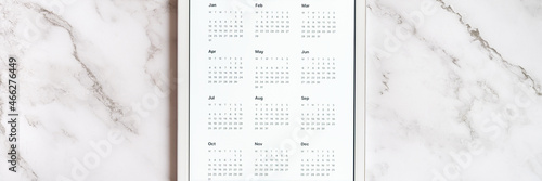 tablet computer with an open app of calendar for unspecified date year without date on a gray marble background. concept business or to do list goals with technology using. top view  flat lay. banner