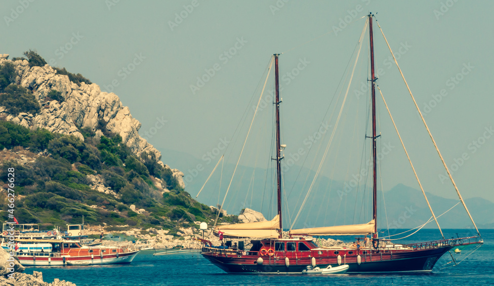 Αυτοκόλλητο Luxury twin-masted sailing vessel on anchor off a Mediterranean beach