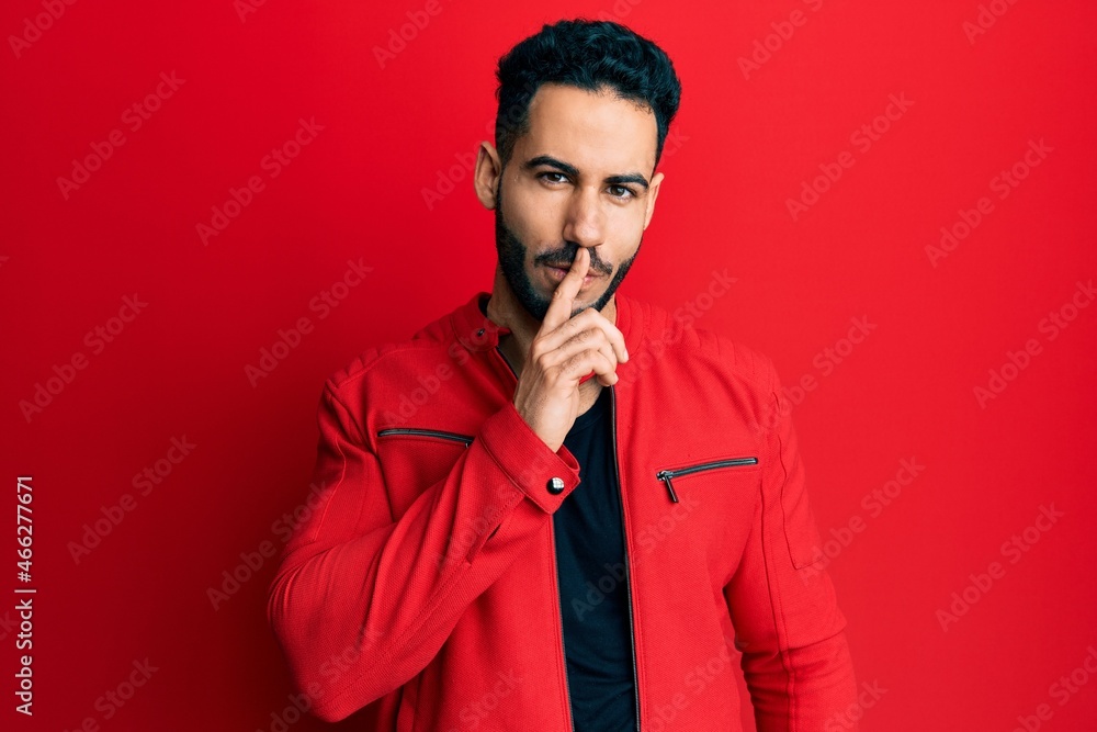 Young hispanic man wearing red leather jacket asking to be quiet with finger on lips. silence and secret concept. Young hispanic man wearing red leather jacket asking to be quiet with finger on lips. silence and secret concept.