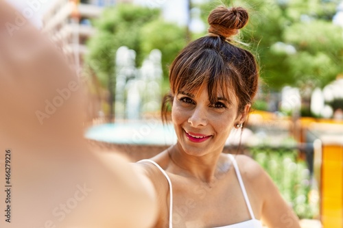 Young hispanic woman smiling happy making selfie by the camera at the city.